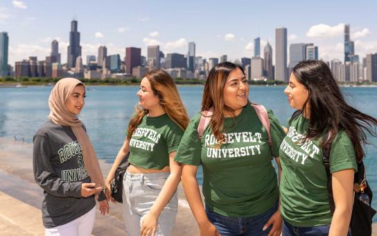Four students in ϰſ shirts with the Chicago skyline in the background